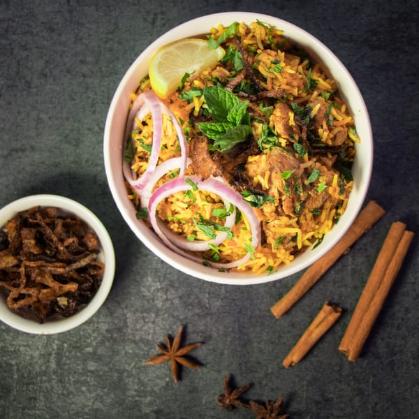 Dasara Indian Cuisine's biryani with lemon, onions, and mint, alongside fried onions and spices.