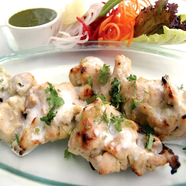 Dasara Indian Cuisine's creamy chicken tikka, garnished with cilantro, served with green chutney and salad.